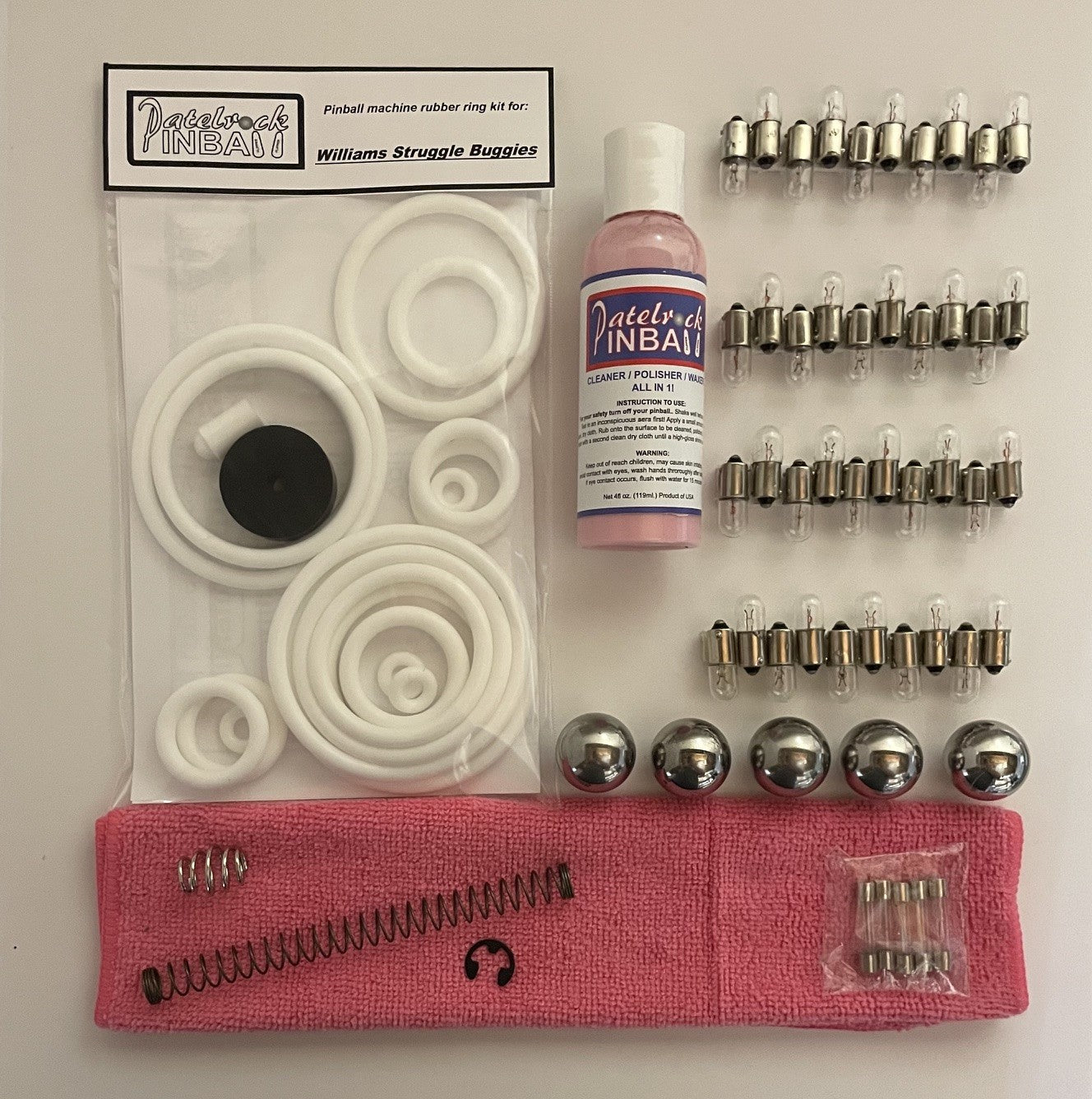 Pinball machine maintenance kit with rubber rings, bulbs, and cleaning solution on a white background.